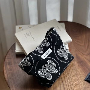 Detail of black canvas makeup bag with butterfly embroidery and simple wish label