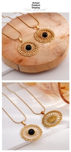 Detail of gold-plated sunburst pendant necklace with a black bead on a snake chain