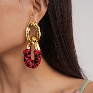 Close-up of golden lava-textured metal rings with red and black leather-wrapped details