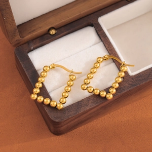 Golden rectangular beaded hoop earrings for women displayed in a vintage jewelry box
