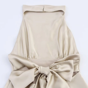 Détail de robe en satin champagne avec col bénitier drapé et grand nœud décoratif à la taille