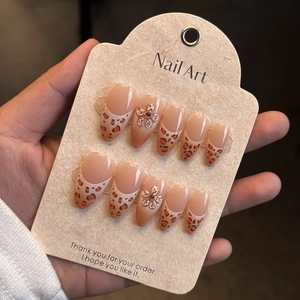 Detail of almond-shaped leopard print press-on nails with 3D flowers and red rhinestones