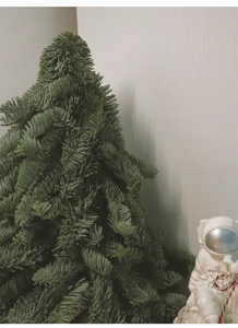 Close-up of a realistic mini green Christmas tree with a white astronaut figurine