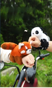 Detailed view of plush panda and red panda snap bracelets worn on the wrist outdoors