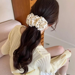 Close-up of a polka dot silk satin banana clip on woman's hair in a warm interior
