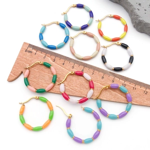 Detail showing various colorful enamel bamboo hoop earrings with a measuring ruler