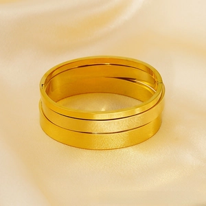 Detailed macro view of a 18K gold brushed stainless steel minimalist hinged bangle set