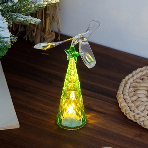 Mini green glowing Christmas tree with bird topper on a wooden desk for home decor