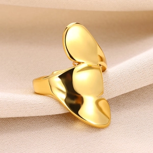 Macro detail of a polished gold butterfly-shaped ring on elegant beige silk fabric