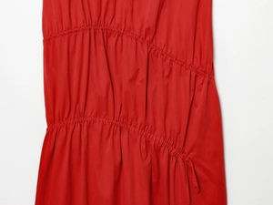 Détail de la robe midi rouge montrant les plis diagonaux et la texture du tissu lisse