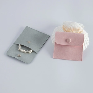 Detail view of velvet jewelry pouches in grey and pink with metal snap button closures