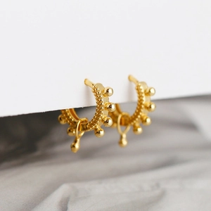 Detail view of golden hoop earrings with bead decor and hanging water drop pendants