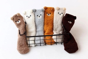 Gros plan de chaussettes en polaire corail avec oreilles d'ours 3D dans un panier noir