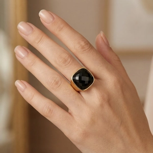 Macro shot of a square black faceted crystal set in a wide gold-plated stainless steel ring