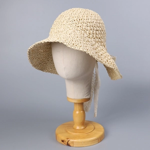 Detail of wide brim straw sun hat with delicate white lace ribbon ties for summer