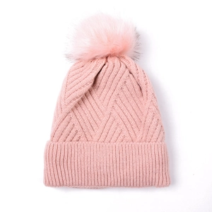 Detail of pink knitted beanie with chevron pattern and fluffy faux fur pom-pom