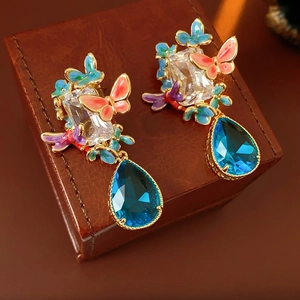 Close-up of vintage butterfly earrings with blue teardrop gems and enamel details