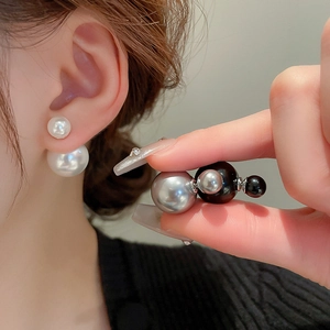 Close-up of double-sided pearl earrings in white, silver-grey and black finishes