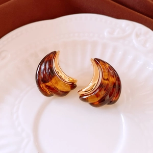 Close-up of vintage amber resin crescent earrings with 18K gold plated metal edges
