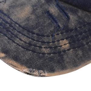 Macro detail of distressed denim baseball cap brim with vintage washed finish and stitching