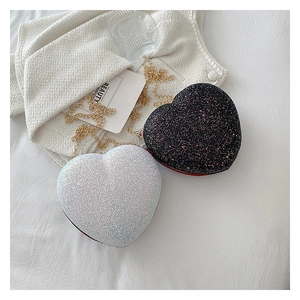 Close-up of heart-shaped sequin bags with golden chains on a decorative background