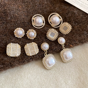 Macro view of vintage gold geometric earrings with pearls and rhinestones on knit fabric