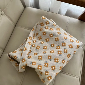 Close-up of yellow flower embroidery and simple wish label on beige canvas tote bag
