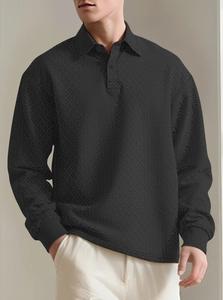 Detailed view of men's long-sleeve polo shirt featuring black textured jacquard knit fabric