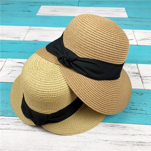 Dettaglio di due cappelli di paglia pieghevoli con fiocchi neri su sfondo in legno azzurro
