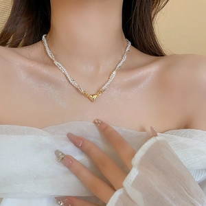 Close-up of pearl necklace with gold heart pendant worn on neck with elegant lighting