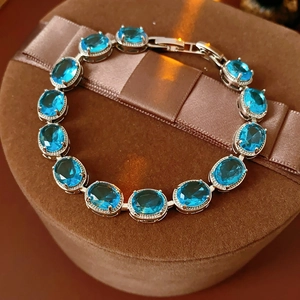 Detail of oval blue zircon bracelet with 13 stones on a brown velvet jewelry stand