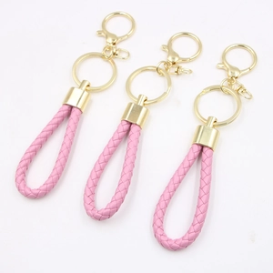 Three pink braided leather keychains with gold metal rings on a white background