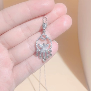 Close-up of a silver-toned necklace featuring a hollow circular pendant with teardrop tassels