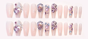 Close-up of pink gradient coffin nails with large crystals, bows, and glitter sparkles