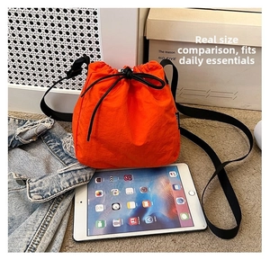 Orange nylon drawstring bucket bag shown next to an iPad for size comparison