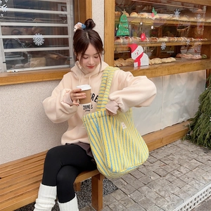 Close-up of fluffy striped plush tote bag interior with model in a lifestyle bakery setting