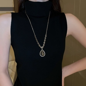 Gros plan d'un collier en V avec pendentif en cristal goutte d'eau et chaîne dorée