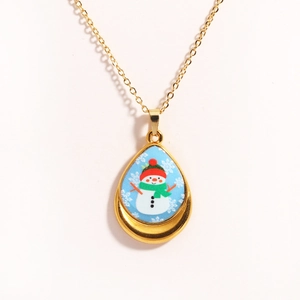 Macro detail of teardrop gold necklace with blue snowman and snowflake patterns