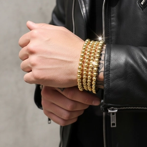 Close-up of four-piece set 18K gold plated beaded elastic bracelets worn with leather jacket