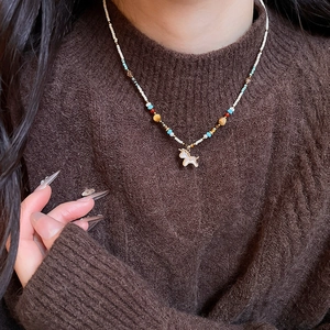 Chinese style beaded necklace with horse pendant on brown sweater background