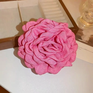 Close-up of pink fabric rose hair claw clip with detailed petal layers on a vanity table
