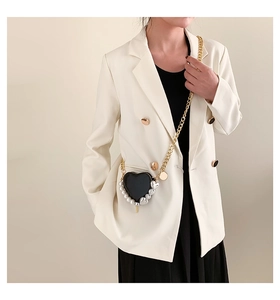 Détail du sac coeur en cuir noir avec bordure en perles et fine chaîne dorée