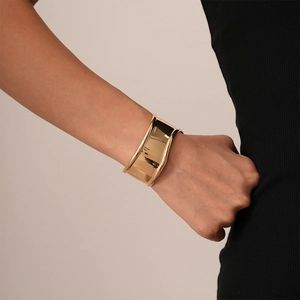 Close-up of irregular wave-edged wide gold metal cuff bracelet on wrist