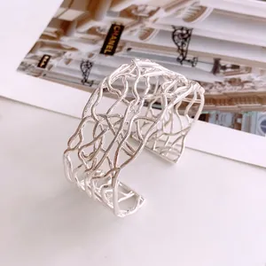 Minimalist silver open cuff bracelet featuring an artistic cross hollow woven design