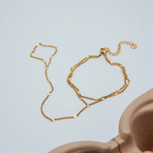Gros plan du bracelet de doigt en acier inoxydable doré avec chaîne et perles fines