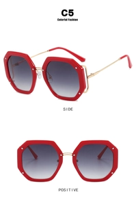 Detail view of red hexagonal sunglasses with gradient lenses and slim gold metal temples
