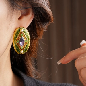 Macro detail of vintage baroque earring with green enamel and purple gemstone on model