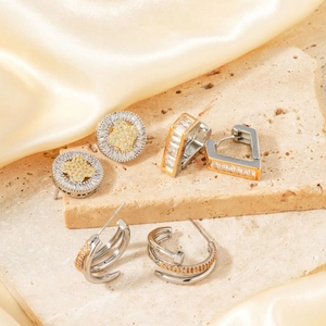Golden geometric earrings set with cubic zirconia on elegant champagne silk background