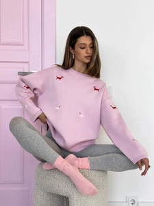 Detail of pink knitted sweater with red sausage dog embroidery and cozy textures