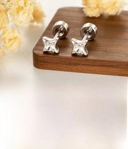 Macro detail of silver four-pointed star ear stud setting with titanium steel screw post